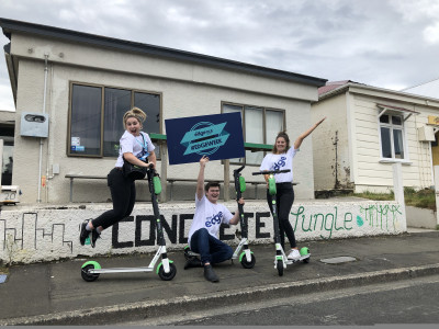 Mediaworks image of three people in front of house posing with Lime scooters